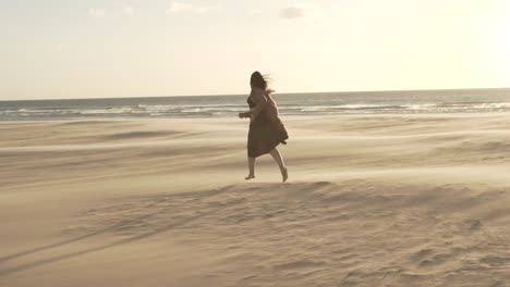 Woman-running-on-sandy-shore-on-windy-day