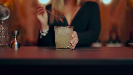 Anonymous-woman-mixing-and-serving-cocktail-during-work-in-stylish-bar