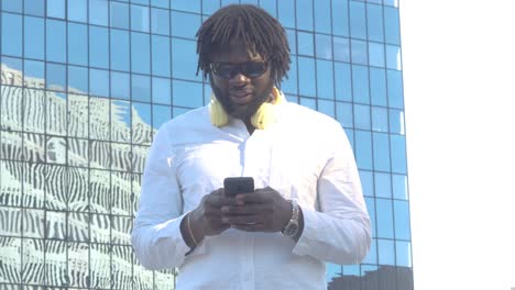 Stylish-black-man-watching-smartphone-on-urban-pavement