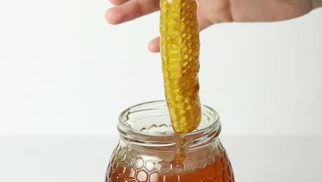 Person-taking-honeycomb-from-jar-with-honey