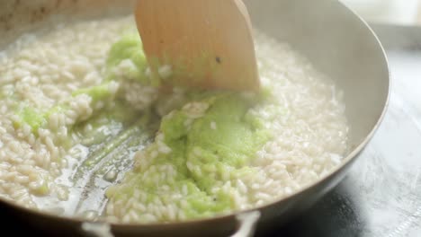Crop-cook-stirring-risotto-with-pesto-sauce-in-pan