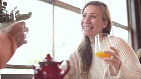 Smiling-woman-talking-to-crop-friend-in-restaurant
