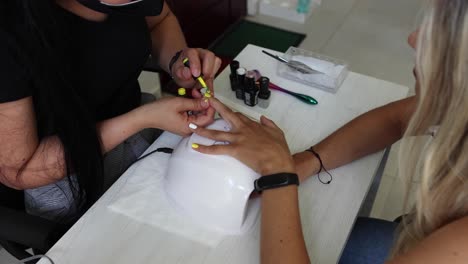 Anonymous-ethnic-doing-manicure-to-client-and-applying-nail-polish