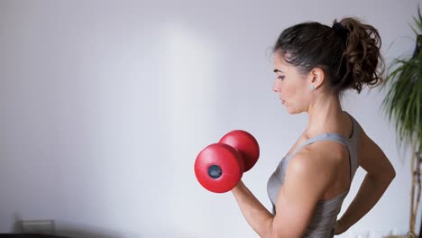 Strong-sportswoman-exercising-with-dumbbell-on-gray-background