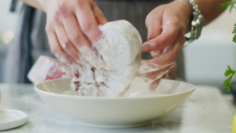 Woman-rolling-veal-shank-in-flour-before-frying