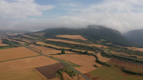 Campos-Agrícolas-Cerca-De-Montañas-Bajo-Un-Cielo-Azul-Nublado