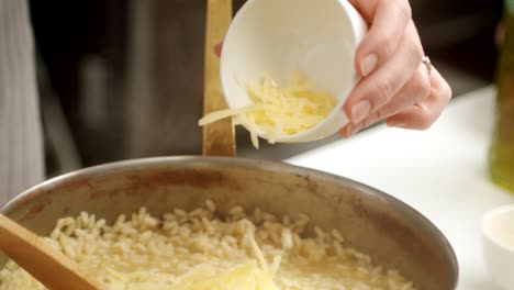 Crop-cook-preparing-risotto-with-cheese-and-butter