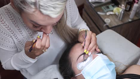Beautician-applying-eyelashes-on-face-of-woman