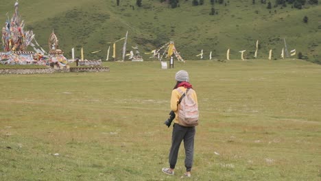 Female-tourist-with-photo-camera-walking-near-flags-and-admiring-landscape
