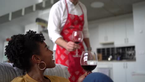 Fröhliches-Multiethnisches-Paar,-Das-Zu-Hause-Gläser-Mit-Wein-Anstößt