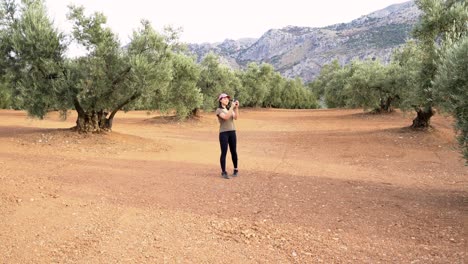 Woman-walking-and-taking-pictures-of-olive-grove