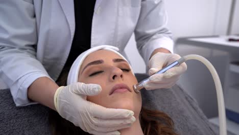 Cosmetologist-doing-microdermabrasion-procedure-for-woman-in-clinic