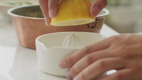 Crop-person-juicing-lemon-in-kitchen