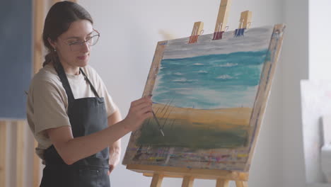 Young-woman-painting-teacher-demonstrates-the-technique-of-applying-acrylic-painting-on-canvas