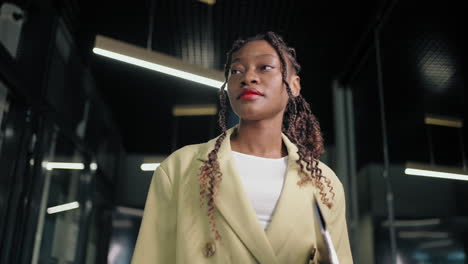 A-black-businesswoman-walks-down-the-hallway-of-the-office-smiling