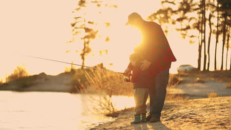 Hermosa-Puesta-De-Sol-En-La-Orilla-Del-Río,-El-Viejo-Pescador-Y-Su-Pequeño-Hijo-O-Nieto-Están-Pescando-Juntos