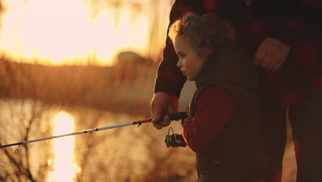 cute-boy-and-his-granddad-are-fishing-together-on-river-coast-in-sunset-resting-in-nature-in-summer