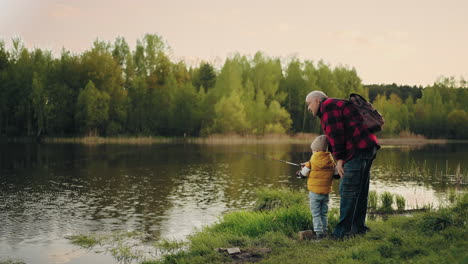 fishing-on-beautiful-shore-of-forest-lake-little-boy-and-grandfather-are-catching-fish