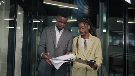 black-man-and-woman-work-in-office-of-big-company-discussing-agreement-before-business-meeting