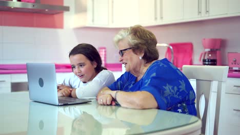 Positive-girl-teaching-grandmother-watching-videos-on-laptop-at-home