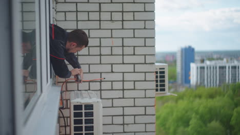 A-man-at-high-altitude-installs-air-conditioning.-Installation-of-the-external-unit-of-the-Air-Conditioning-System.-Summer-cooling-of-the-air-in-the-big-city