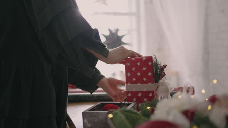 Eine-Junge-Frau-Verpackt-Ein-Weihnachtsgeschenk-In-Rotes-Papier-Und-Bindet-Es-Mit-Bändern-Zusammen.