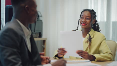 Una-Mujer-Negra-Feliz-Y-Segura-Recluta-A-Un-Empleador-Que-Le-Da-La-Mano-Y-Que-La-Contratan-En-Un-Nuevo-Trabajo.-Una-Joven-Y-Sonriente-Gerente-Profesional-Estrecha-La-Mano-De-Un-Cliente-Negro-O-De-Un-Cliente-Que-Realiza-Una-Reunión-En-La-Oficina-De-Negocios