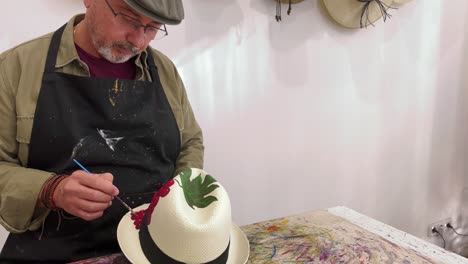 Talented-male-artist-painting-on-hat-in-creative-studio