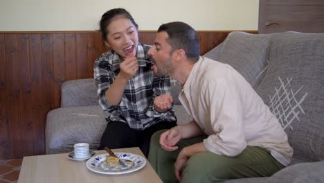 Multiethnic-couple-eating-tasty-pancakes-at-home