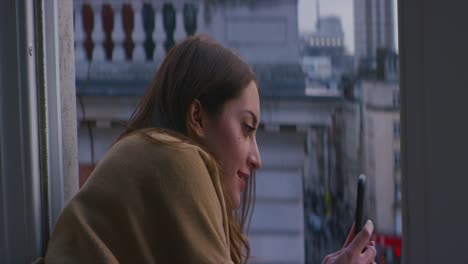 Woman-making-video-of-city-street-of-london-from-a-window-with-smartphone