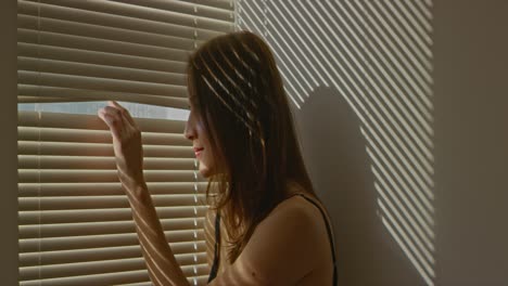 Woman-peeking-out-through-blinds