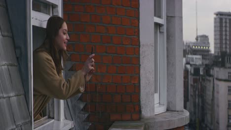 Woman-making-video-of-city-street-of-london-from-a-window-with-smartphone