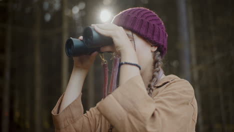 Female-explorer-observing-through-binoculars-in-forest