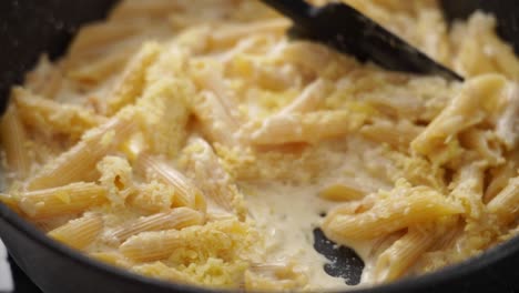 Cook-stirring-cheese-to-creamy-pasta