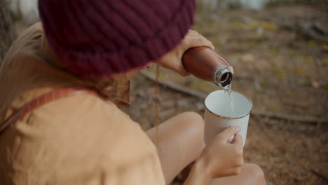 Female-explorer-pouring-water-in-mug-from-bottle