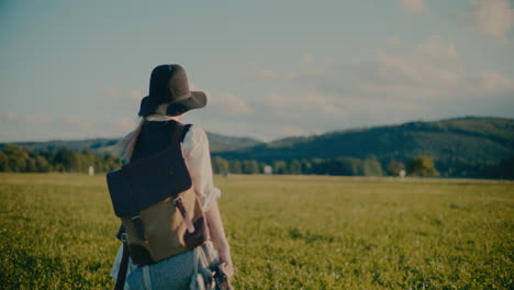 Woman-Walking-In-Meadow-Carrying-Backpack