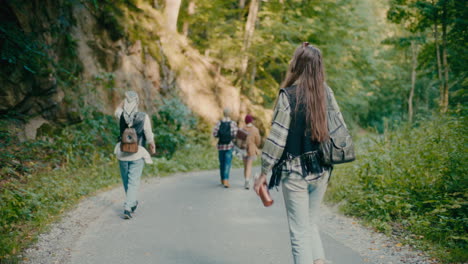 Woman-Walking-With-Tourist-Friends-On-Footpath-In-Forest