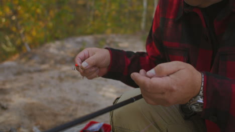 fisherman-is-choosing-and-fixing-baits-and-lures-on-hook-of-rod-closeup-view-of-hands-man-is-angling