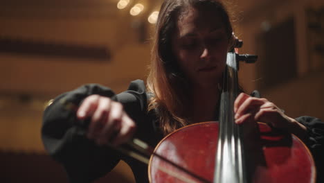 Talentierte-Frau-Spielt-Violoncello-Im-Musiksaal-Cellistin-Probt-Auf-Der-Bühne-Des-Musiksaals