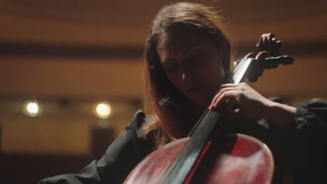 Mujer-Bonita-Músico-Está-Tocando-El-Violonchelo-En-El-Music-Hall-Violonchelista-Femenina-En-La-Escena-De-La-ópera