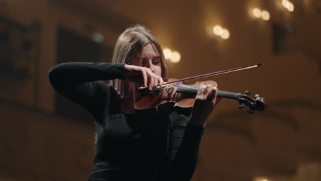 young-female-violinist-is-learning-to-play-violin-in-rehersal-hall-or-on-scene-in-opera-house-or-music-hall