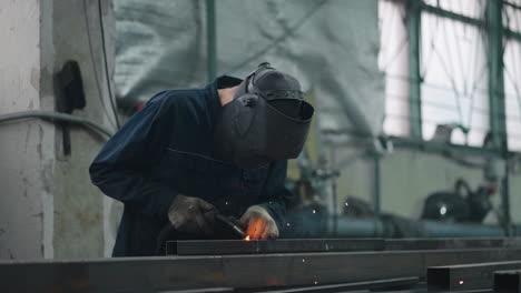 A-working-welder-in-a-protective-mask-connects-metal-parts-with-gas-or-electric-welding-in-slow-motion