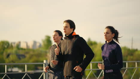 team-of-yougn-joggers-is-training-in-summer-morning-three-athletic-persons-are-running-together