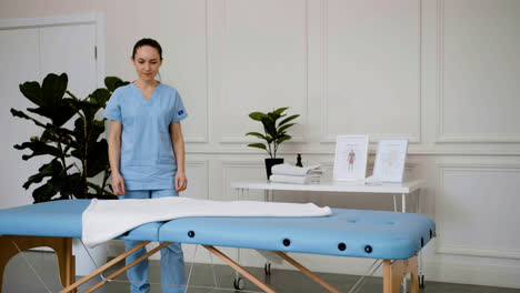 Physiotherapist-preparing-massage-bed