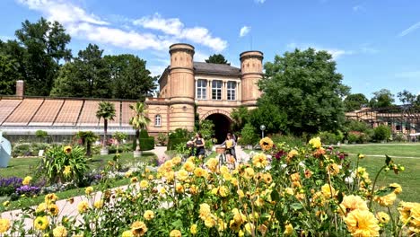 Gente-Caminando-Frente-A-La-Hermosa-Torre-Barroca-Y-Disfrutando-De-Un-Día-Soleado-En-El-Jardín-Botánico-De-Karlsruhe