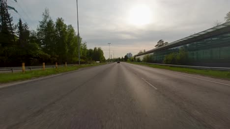 Un-Automóvil-Que-Viaja-Rápidamente-Por-Una-Carretera-Entre-árboles-Y-Edificios-En-Un-área-Metropolitana