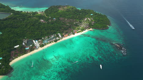 Aerial-panoramic-overview-of-fringing-reef-and-sandy-beach-of-koh-phi-phi,-overview-of-hotel-homes