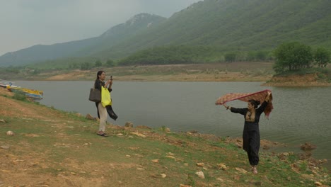 Well-dressed-South-Asian-female-tourists-posing-and-clicking-photographs-at-scenic-hilly-landscape-under-the-cloudy-sky