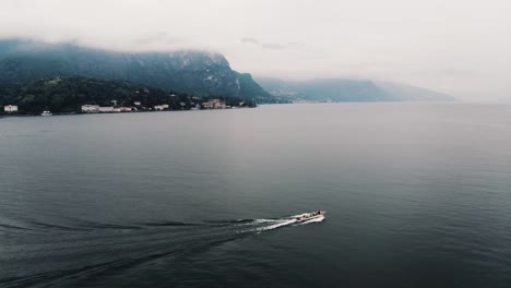 Vista-Aérea-De-Un-Barco-Privado-Navegando-Por-El-Lago-Como-En-Las-Remotas-Montañas-De-Italia.