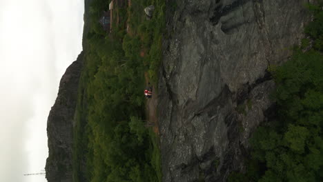 Vertical-View-Of-A-People-Sitting-On-The-Bench-Near-Edge-Of-Rocky-Cliff-In-Fister,-Stavanger-Norway